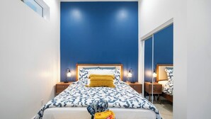Un dormitorio con cama, mesitas de noche y un espejo.