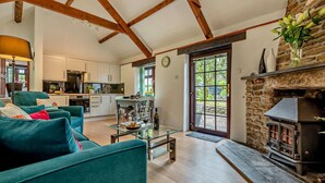 A spacious living area with a sofa, a glass coffee table, a fireplace, and a kitchen in the background. - 1 Bed in Advent (oc-b29387) (Advent)