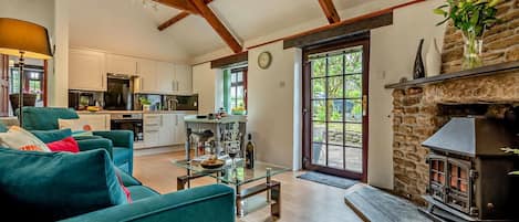 A spacious living area with a sofa, a glass coffee table, a fireplace, and a kitchen in the background.