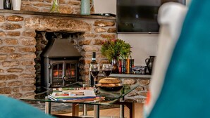 A cozy living room with a stone fireplace, a glass coffee table, and a comfortable seating area. - 1 Bed in Advent (oc-b29387) (Advent)