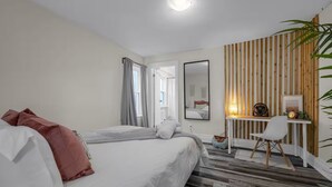 Ein modernes Hotelzimmer mit einem großen Bett, einem Schreibtisch mit Stuhl und einer Wand mit Holzpaneelen.