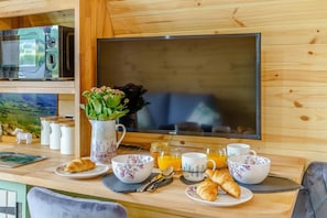 Colazione con croissant, succo d'arancia e un vaso di fiori su un tavolo di legno.