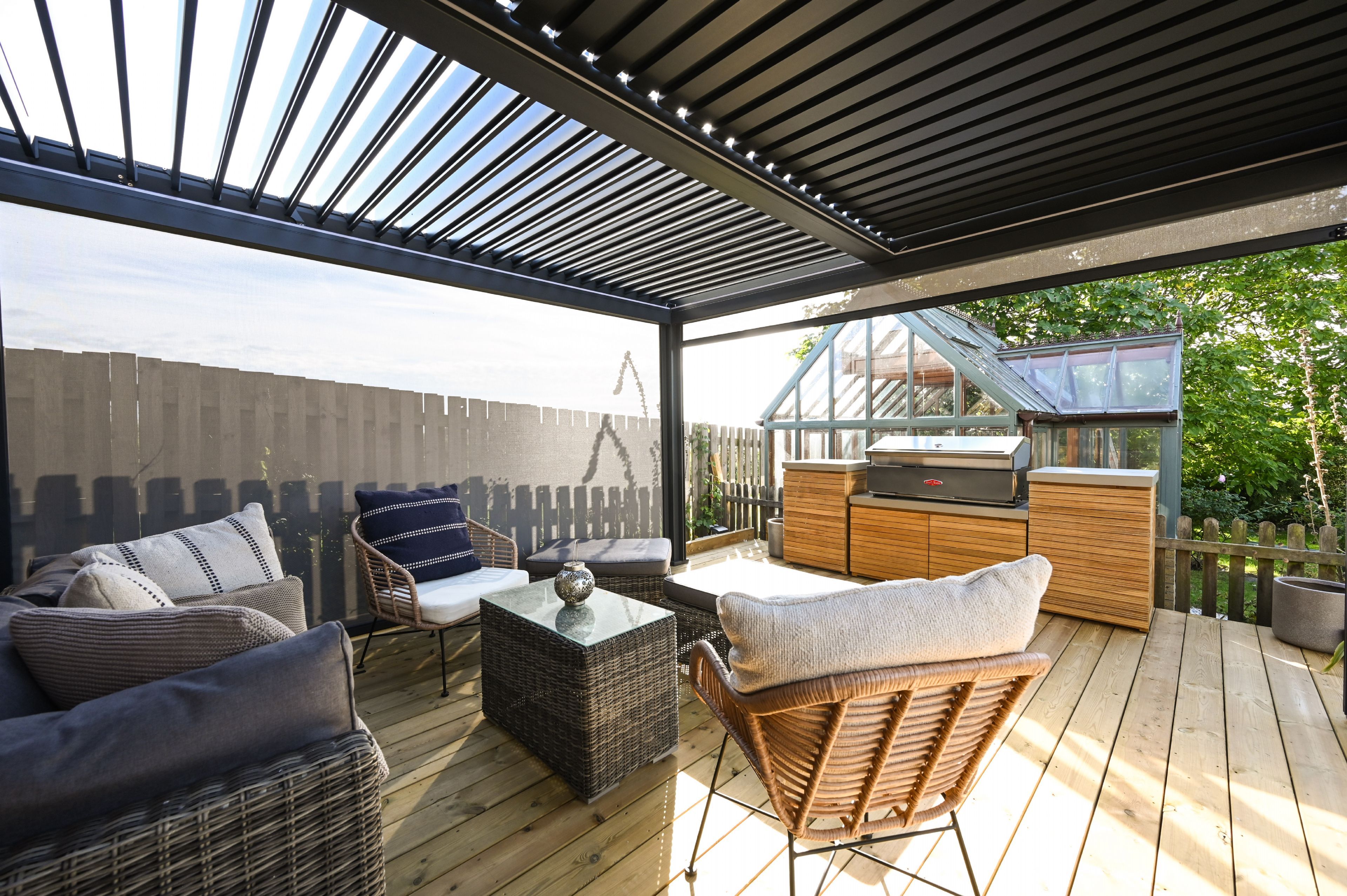 An outdoor patio with wicker furniture, a glass-top table, and a barbecue area.