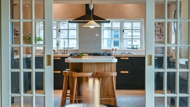 Een moderne keuken met een centraal eiland, hanglampen en uitzicht op de eethoek.
