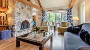 Una sala de estar acogedora con chimenea de piedra, vigas de madera, un sofá y una mesa de centro.
