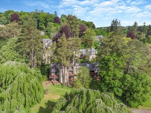 Un vaste domaine comprenant plusieurs bâtiments, entouré d’une forêt dense.