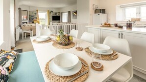 A modern dining area with a white table set for four, surrounded by white chairs. - 2 Bed in St. Minver (oc-r29475) (Saint Minver)