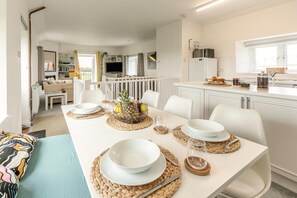 A modern dining area with a white table set for four, surrounded by white chairs. - 2 Bed in St. Minver (oc-r29475) (Saint Minver)