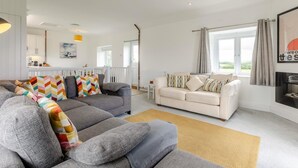 A modern living room with a grey sectional sofa, a white sofa, and a beige rug. - 2 Bed in St. Minver (oc-r29475) (Saint Minver)