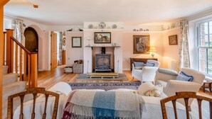 A cozy living room with a fireplace, wooden furniture, and a staircase. - 5 Bed in Morston (oc-s29448) (Morston)