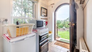 A compact kitchen with a washing machine, a microwave, and a stove. - 5 Bed in Morston (oc-s29448) (Morston)