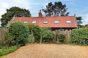 Ein Haus mit rotem Ziegeldach, einem Holzzaun und einem Schotterweg.