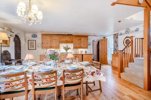 A dining area with wooden furniture, a chandelier, and a staircase.