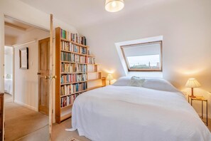 A bedroom with a large bed, a bookshelf, a skylight, and a door leading to another room. - 5 Bed in Morston (oc-s29448) (Morston)