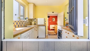 Eine kleine Küche mit Kühlschrank, Spüle und Holzschränken.