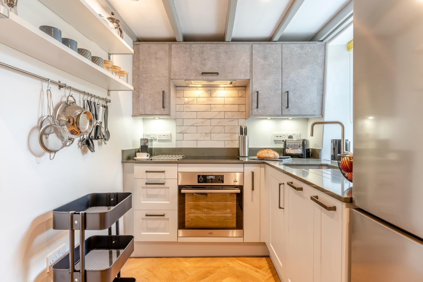 A modern kitchen with white cabinetry, a built-in oven, and a stainless steel refrigerator.
