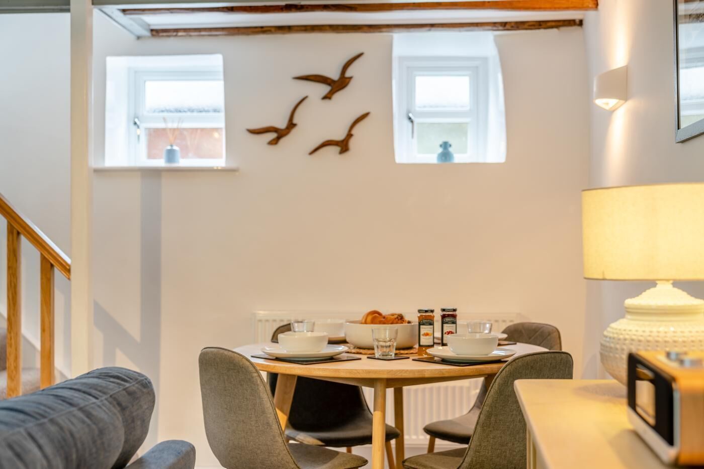 Un coin repas comprenant une table ronde, des chaises, une lampe et des éléments de décoration murale.