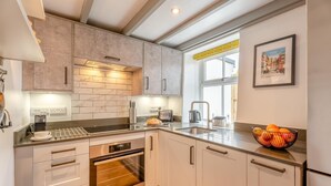 Una cocina moderna con gabinetes blancos, electrodomésticos de acero inoxidable y un ventanal con vistas a la ciudad.