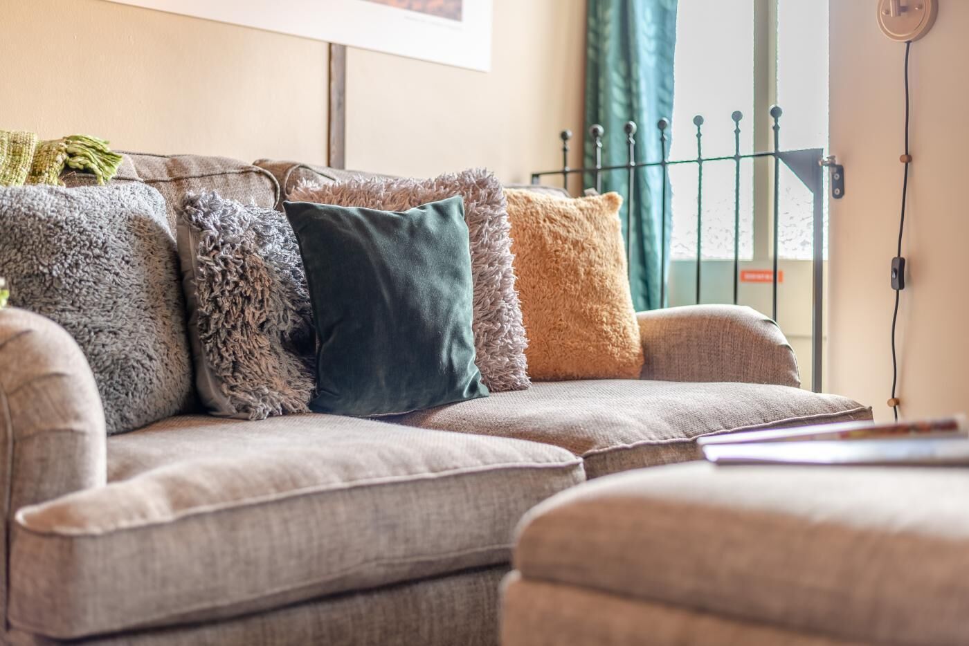 A grey sofa with multiple cushions in various textures and colors.