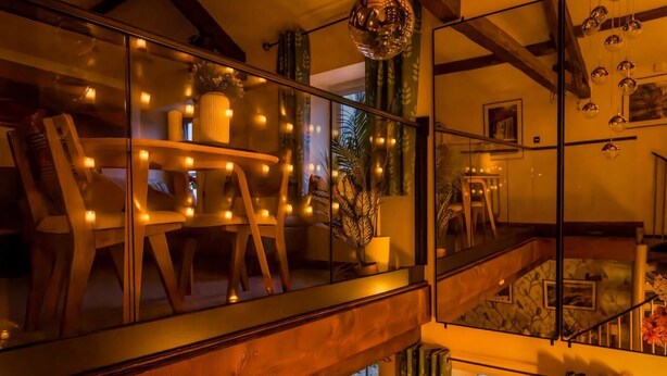 A cozy interior with a wooden staircase, a dining area with chairs, and a large mirror reflecting the room. - 1 Bed in Reeth (oc-t29540) (Reeth)