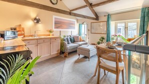 A cozy kitchen with a dining area, wooden beams, a clock, and a view of the outdoors. - 1 Bed in Reeth (oc-t29540) (Reeth)