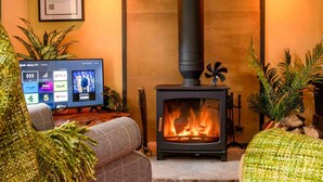 A cozy living room with a fireplace, a television displaying streaming services, and comfortable seating. - 1 Bed in Reeth (oc-t29540) (Reeth)