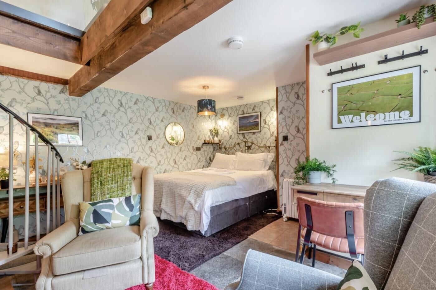 A cozy bedroom with a bed, a desk, and a chair. There is a staircase leading to another level.