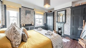 A bedroom with a large bed, a fireplace, a mirror, and a wardrobe. - 2 Bed in Rye (oc-86094) (Rye)