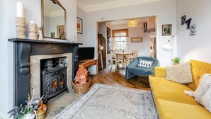A living room with a fireplace, a sofa, a dining area, and a hallway leading to another room. - 2 Bed in Rye (oc-86094) (Rye)