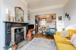 A living room with a fireplace, a sofa, a dining area, and a hallway leading to another room. - 2 Bed in Rye (oc-86094) (Rye)