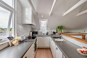Eine moderne Küche mit großem Fenster, weißen Schränken, einer Mikrowelle, einem Toaster und einer Spüle.