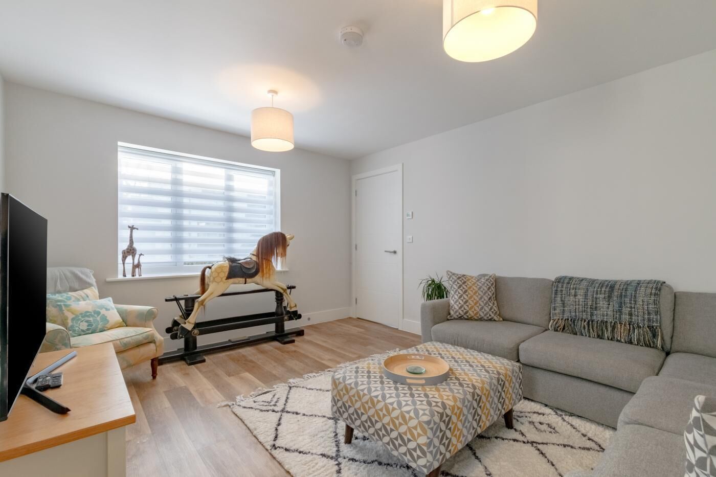 A modern living room with a sofa, ottoman, and a rocking horse.