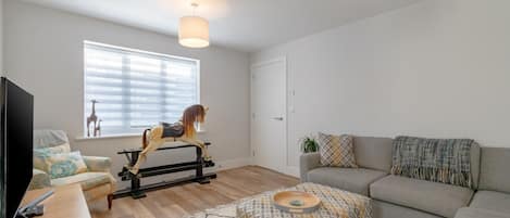 A modern living room with a sofa, ottoman, and a rocking horse.