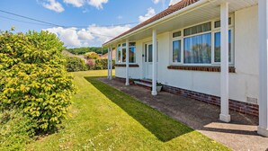 Ein zweistöckiges Haus mit überdachter Veranda, Klinkerfundament und großen Fenstern.
