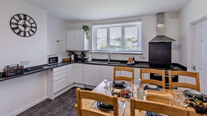 Eine moderne Küche mit weißen Schränken, einer schwarzen Arbeitsplatte, einem eingebauten Backofen und einem Fenster mit Jalousien.