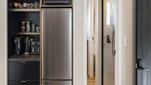 Eine Küche mit einem Edelstahlkühlschrank, einer Mikrowelle und einer Kaffeemaschine auf einem Regal.