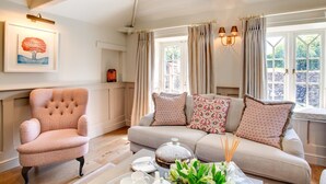 Ein gemütliches Wohnzimmer mit einer gepolsterten Couch, einem gemusterten Sessel und einem Couchtisch mit Kuchen und Dekoration.
