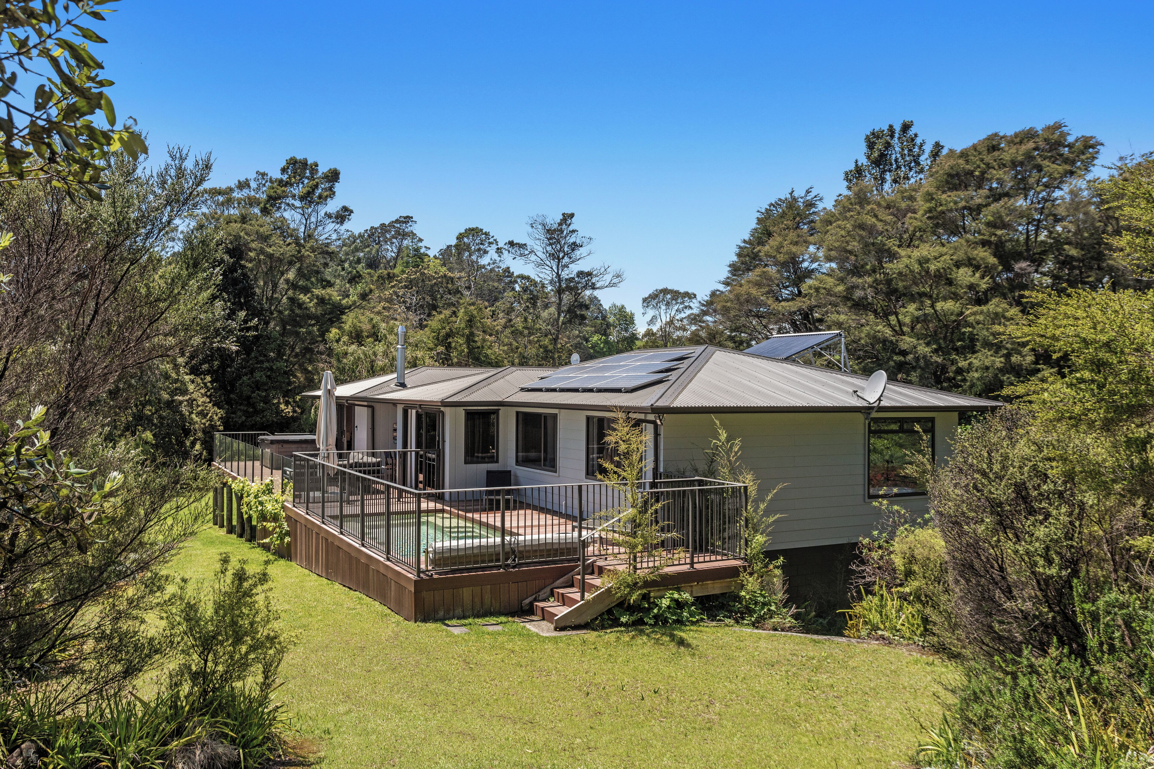A house with a deck, a swimming pool, and a satellite dish.