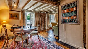 A traditional room with exposed wooden beams, a round table with chairs, a patterned rug, and a wall-mounted artwork. - 3 Bed in Trunch (oc-t29507) (Trunch)