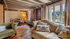 A cozy room with exposed wooden beams, a dining area with a table and chairs, and a sofa with decorative pillows. - 3 Bed in Trunch (oc-t29507) (Trunch)