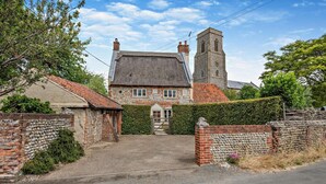 A traditional stone house with a thatched roof, a prominent tower, and a gated entrance. - 3 Bed in Trunch (oc-t29507) (Trunch)