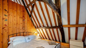 A cozy room with a sloped ceiling, wooden walls, a bed with white linens, a bedside table, and a chair. - 3 Bed in Trunch (oc-t29507) (Trunch)