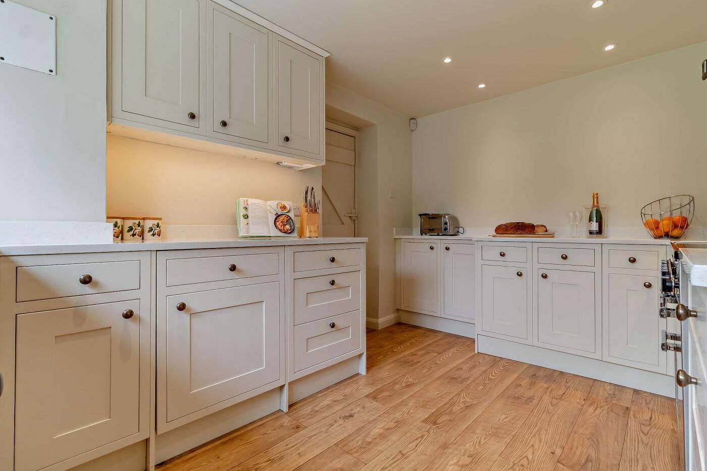 A kitchen with white cabinets, wooden flooring, and a built-in oven.