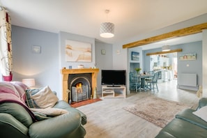 A modern living room with a fireplace, a television, and a dining area with chairs and a table. - 2 Bed in Heacham (oc-p29546) (Heacham)