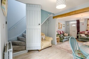 A staircase with a white railing, a green sofa, a blue chair, and a wooden ceiling beam. - 2 Bed in Heacham (oc-p29546) (Heacham)