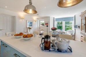 Une cuisine moderne dotée d’un îlot central, de meubles blancs et offrant une vue sur l’extérieur.