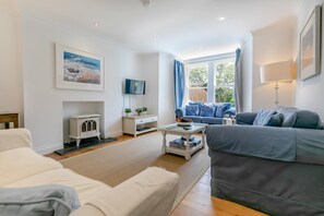Un salon avec un canapé, une table basse, un téléviseur et une cheminée.