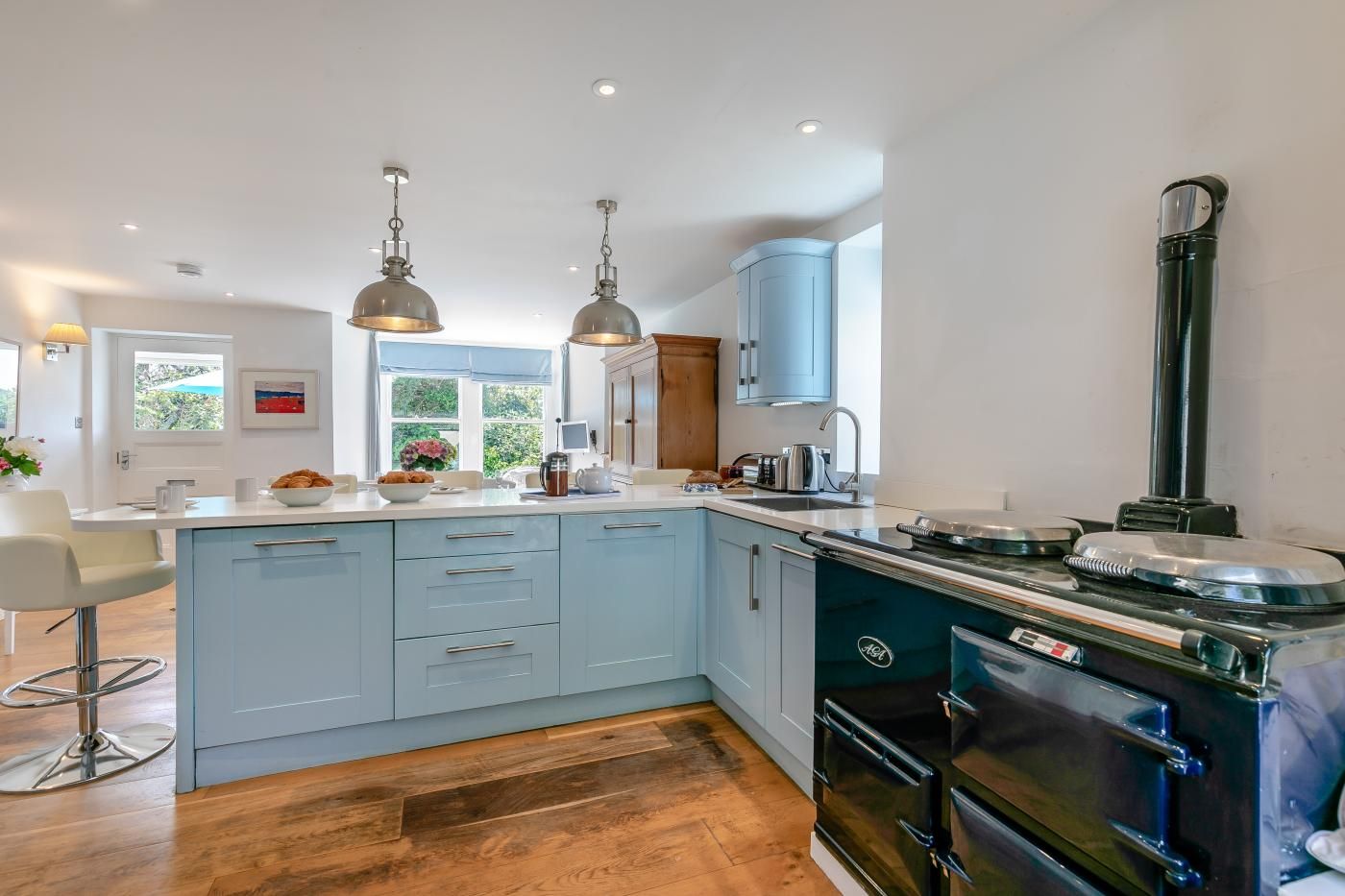 A modern kitchen with a central island, pendant lighting, and a built-in stove.