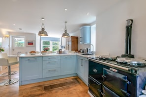 A modern kitchen with a central island, pendant lighting, and a built-in stove. - 5 Bed in Trebetherick (oc-b29371) (La Mohay)