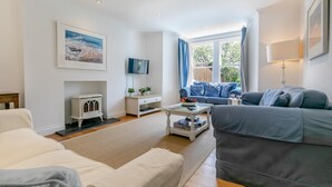 A modern living room with a sofa, a coffee table, a TV, and a fireplace. - 5 Bed in Trebetherick (oc-b29371) (La Mohay)